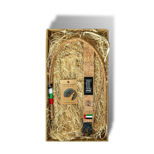 Open Kraft box that has natural hey as stuffing, 1 metal magnet with the UAE map silhouette, cork wrist strap keychain with the official "Year of the Fiftieth" logo and UAE flag and a cork lanyard wrapped in thread of red, white, green and black.